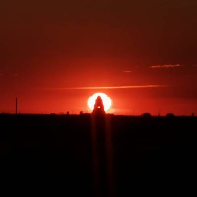 Das Völkerschlachtsdenkmal in Leipzig und dahinter die untergehende Sonne.